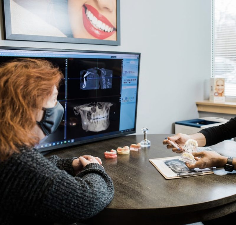 A three dimensional jaw scan on a monitor and dental models on a table during a full arch planning consultation with Dr. Arpan Nalin Patel.
